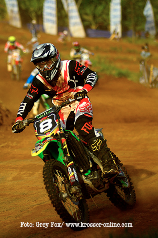 Mehrere Motorradfahrer mit Helmen nehmen an einem Rennen teil, mit Text am unteren Bildrand.