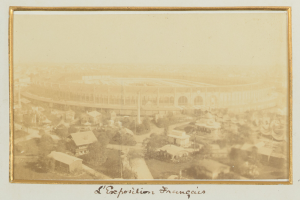 Altes Schwarz-Weiß-Foto eines Stadions in städtischer Umgebung mit umliegenden Gebäuden, Bäumen und Strommasten, das Text am unteren Rand enthält.