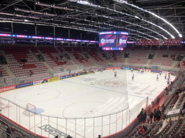 Eishockeyspiel in einer großen Arena zwischen den St. Louis Blues und Detroit Red Wings, mit Zuschauern auf den Sitzplätzen und in der Nähe des Spielfelds, umgeben von einem Zaun und Anzeigebildschirmen.