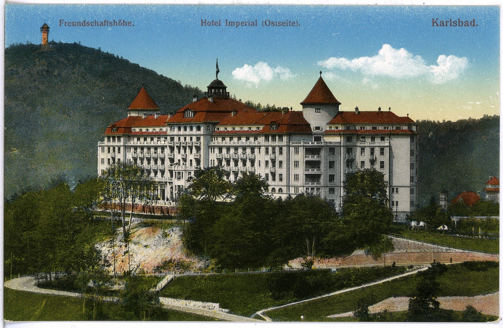 Alte Ansichtskarte des Hotels Imperial in Karlsbad, Deutschland, zeigt ein großes Gebäude mit Fenstern, umgeben von Bäumen, Pflanzen, Gras, einem Weg, einer Baumgruppe, Hügeln und einem bewölkten Himmel, mit Text oben.