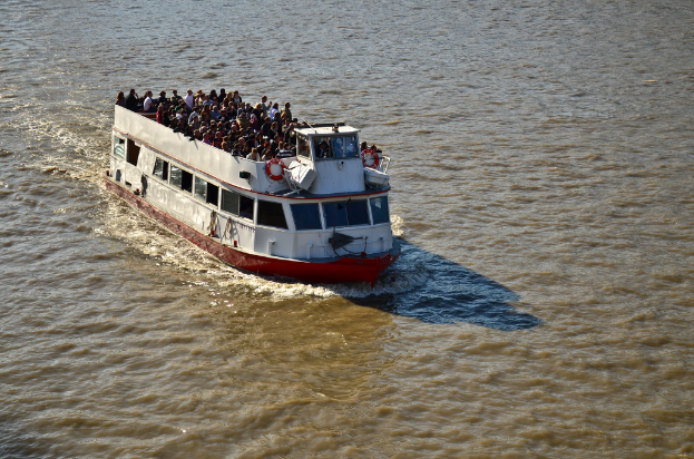 Ein Schiff auf dem Wasser mit vielen Menschen an Deck.