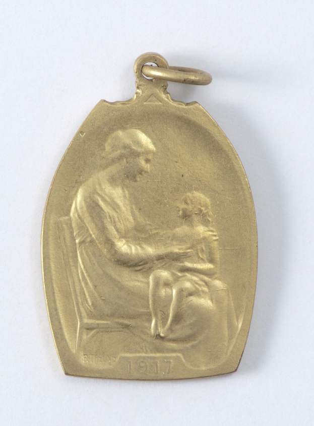 Goldmedaille mit Relief einer Frau in weißer Kleidung mit einem Knoten im Haar, die ein Kind hält und beide sich sanft anschauen, beschriftet mit "Mutter und Kind" in Kursivschrift.