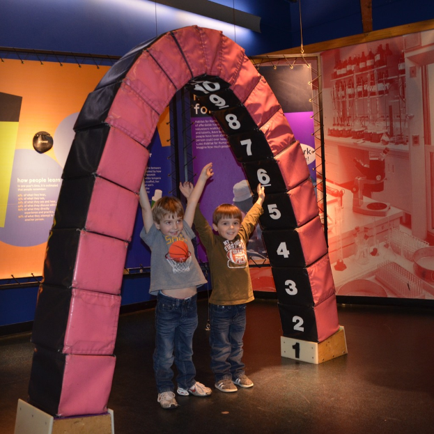Kinder spielen auf einer lustigen Rutschbahn mit Brettern, die auf einem Boden stehen.
