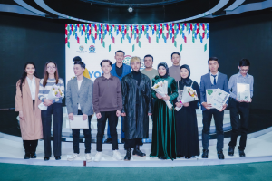 Gruppe von Menschen auf einer Bühne mit Blumensträußen und Urkunden, vor dem Hintergrund "Jugend-Solar-Awards 2019".