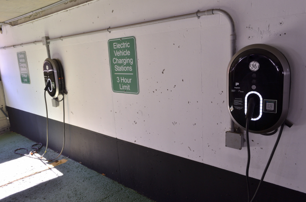 Ladestationen für Elektrofahrzeuge an einer Wand in einer Tiefgarage mit Informationsschildern darunter.