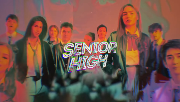 Eine Gruppe von M├Ąnnern und Frauen vor einer Wand mit der Aufschrift 'Senior High'.