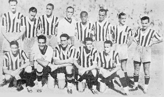 Ein Schwarz-Weiß-Foto einer Fußballmannschaft, bei der einige Spieler stehen und andere auf dem Boden sitzen, und ein Text unten.