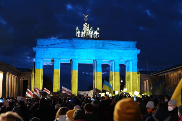 Eine Menschenmenge steht vor dem Brandenburger Tor in Berlin, Deutschland, mit Fahnen und Plakaten in den Händen, auf der rechten Seite ein Banner.