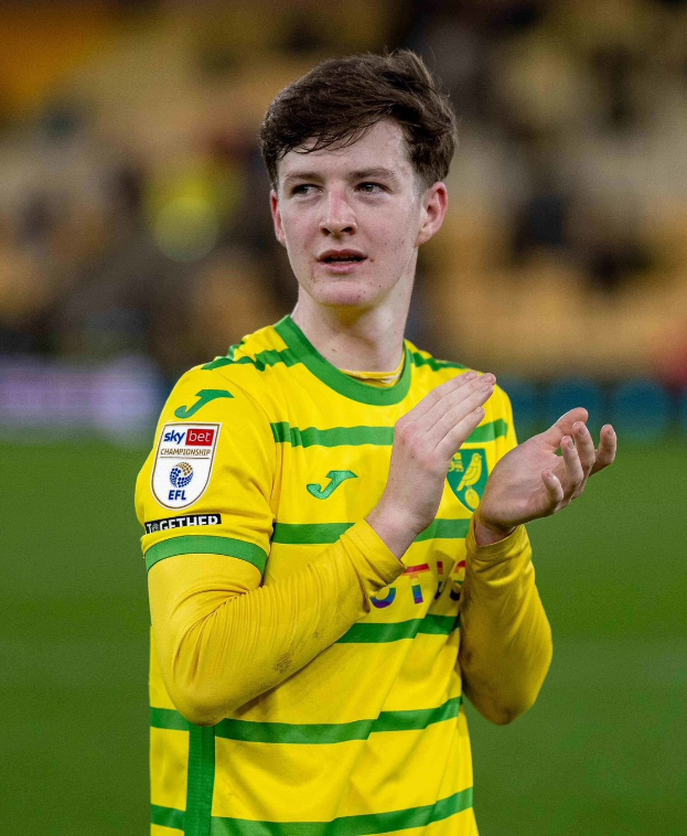 Ein junger Mann in einem gelb-grünen T-Shirt klatscht auf einem Fußballfeld, feiert ein Tor mit einem unscharfen Hintergrund.