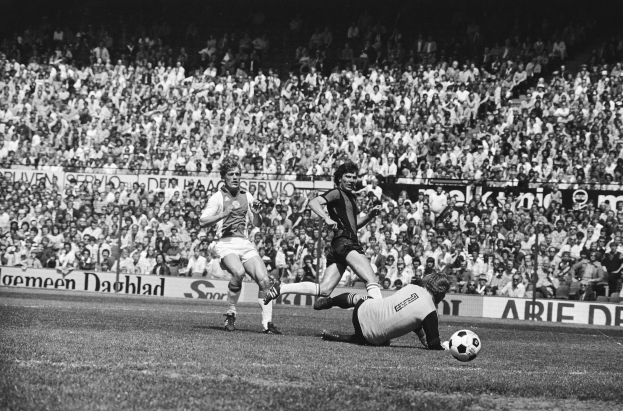 Schwarzes und weißes Foto von Männern, die auf einem Feld Füßball spielen, mit Zuschauern im Hintergrund und einer 'Bundesliga 1978-79 Ajax 1-1 Hannover 96'-Tafel.