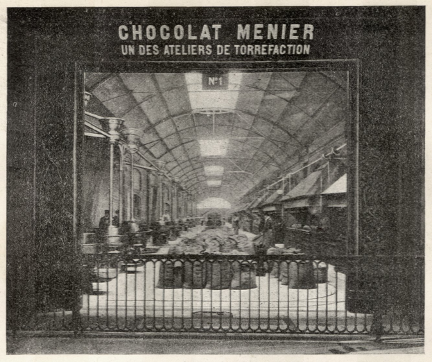 Ein altes Schwarz-Weiß-Foto eines Bahnhofs mit Menschen, Gittern, Pfählen, Lampen und einem Dach, mit dem Text "Chocolat Menier - Un des Ateliers de Torrefaction" oben drauf.