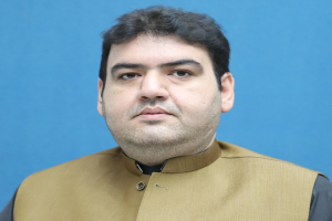 Ein Mann in brauner Weste und schwarzem Hemd steht vor einem blauen Hintergrund und sieht verzweifelt und hoffnungslos aus, wahrscheinlich wegen einer lebenslangen Haftstrafe.