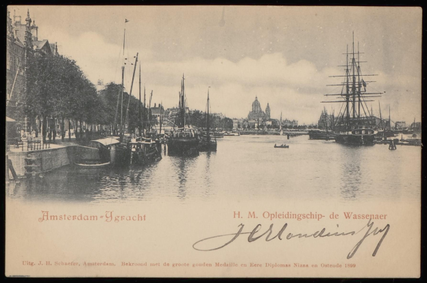 Ein altes Schwarz-Weiß-Foto von Booten, die in einem Hafen mit Gebäuden, Bäumen und Himmel im Hintergrund liegen, mit Text unten lesend "Amsterdam-ygracht - h m opleidingship de wassenaar".