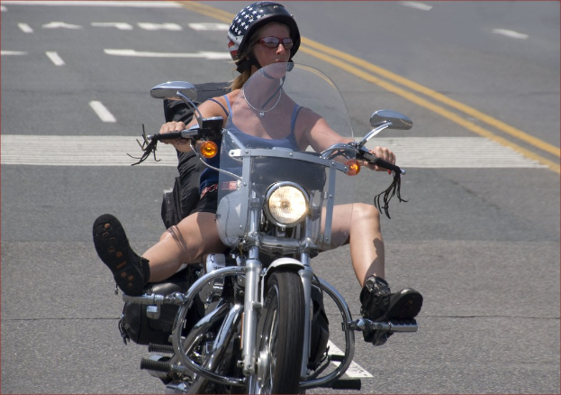 Eine Frau mit einem schwarzen Helm fährt auf der Straße Fahrrad.