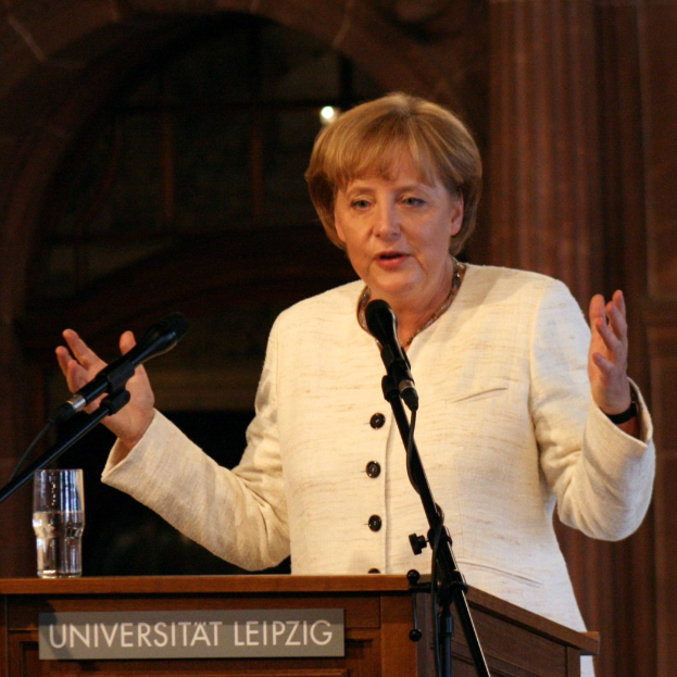 Bundeskanzlerin Angela Merkel bei einer Rede an einem Rednerpult mit Mikrofon und einem Glas Wasser an der Universität Leipzig.
