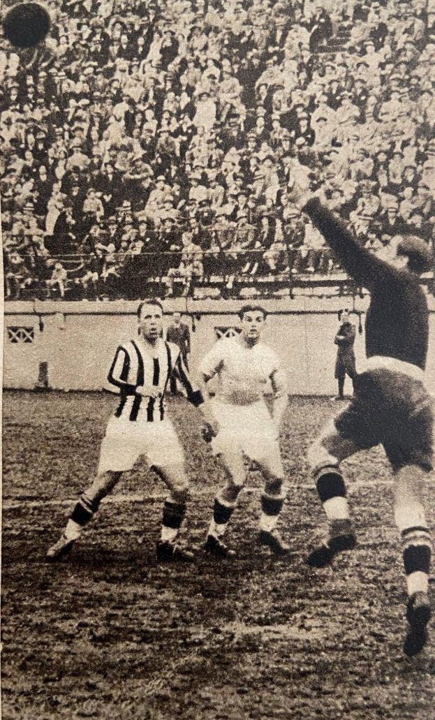 Schwarzes und weißes Foto von Männern, die Fußball spielen, mit Zuschauern auf den Tribünen und einer Wand im Hintergrund, beschriftet mit "Newcastle United v West Bromwich Albion".