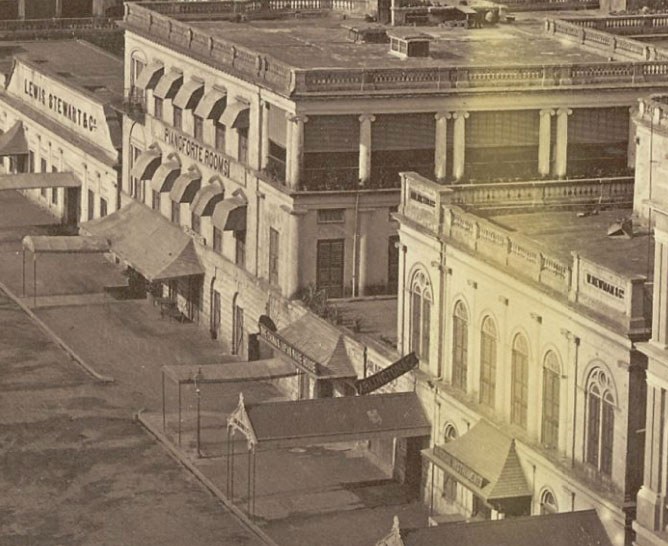 Altes Schwarz-Wei├č-Foto einer Stadtstra├če mit Geb├Ąuden, Fenstern, Pfeilern, Namensschildern, Hütten und Masten.