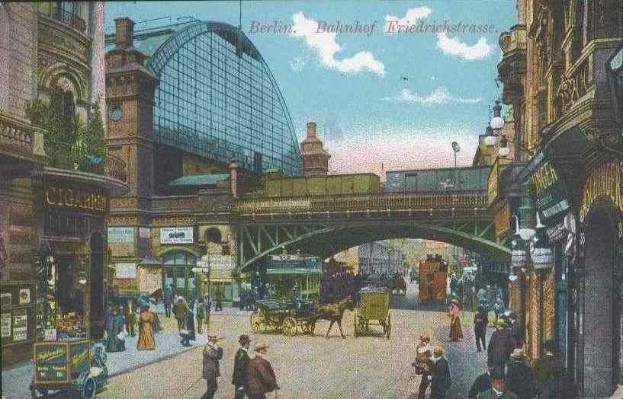 Alte Ansichtskarte einer belebten Straßen in Berlin, Deutschland, mit Passanten, Pferdewagen, Gebäuden, Laternen, einer Brücke und einem bewölkten Himmel mit Text oben.