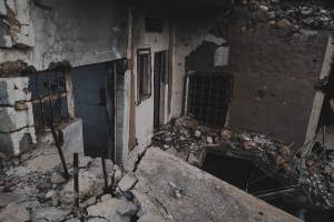 Ein altes, bröckelndes Gebäude mit zerbrochenen Fenstern und herumliegendem Schutt, das einen Zustand des Verfalls und der Vernachlässigung anzeigt.