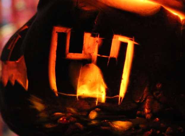 Ein Jack-o'-Lantern mit dem Wort "Halloween" darin eingeschnitzt, von innen beleuchtet, mit einem unscharfen Hintergrund.