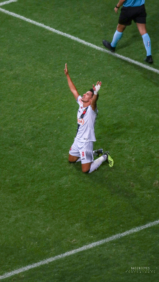 Ein Fußballspieler in Sportbekleidung und -schuhen kniet auf dem Boden und streckt die Arme aus.