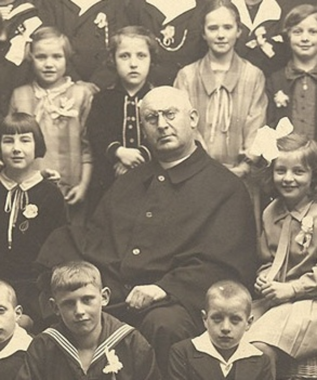 Ein Schwarz-Wei├č-Foto eines strengen Mannes, der in der Mitte sitzt und von einer Gruppe Kinder bewundert wird.