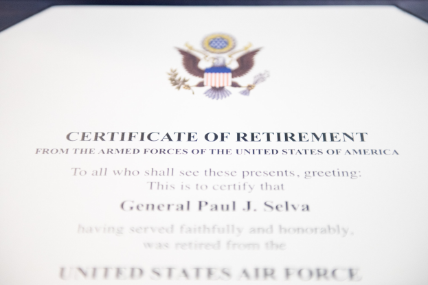Rahmenurkunde für den Ruhestand von der United States Air Force mit blauem Rand, die ein zentrales Sternemblem innerhalb eines Lorbeerkranzes und eine "Ruhestand"-Banderole zeigt.