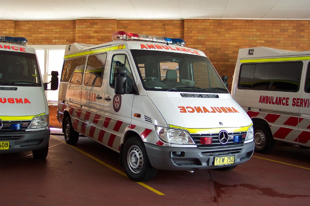 Ein weißer Rettungswagen steht vor einer Backsteinwand.