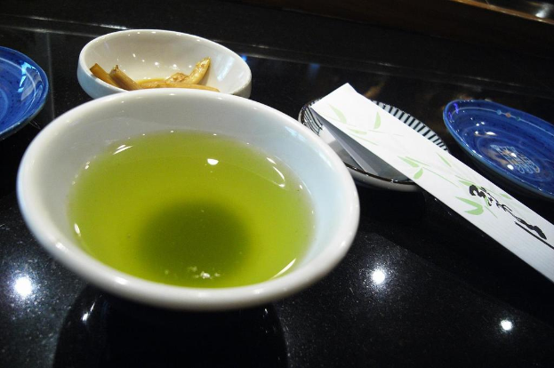 Ein schwarzes Tablett mit einer Schüssel Suppe, einem Teller mit Lebensmitteln und einem unbekannten Gegenstand.